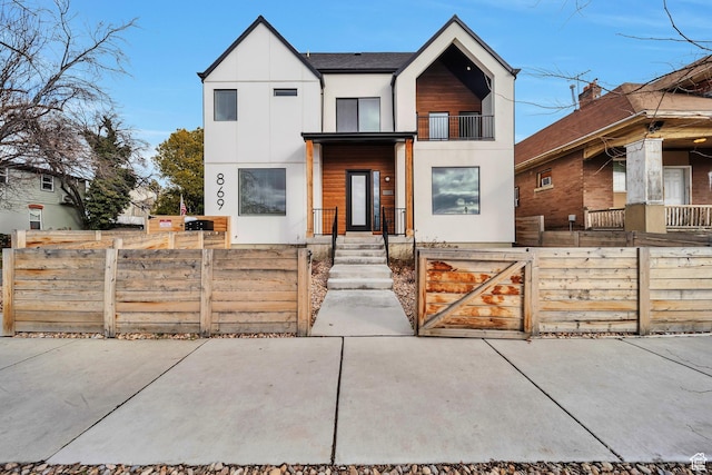 view of front of home with a fenced front yard, stucco siding, a balcony, and a gate