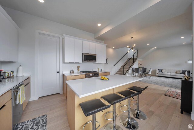869 S Washington St Unit 101, Salt Lake City, UT 84101 - kitchen featuring light wood-style floors, appliances with stainless steel finishes, a breakfast bar area, and a center island