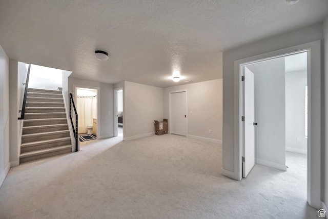 869 S Washington St Unit 101, Salt Lake City, UT 84101 - below grade area featuring carpet flooring, baseboards, a textured ceiling, and stairs
