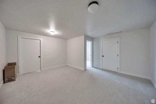869 S Washington St Unit 101, Salt Lake City, UT 84101 - below grade area featuring a textured ceiling, baseboards, visible vents, and light carpet