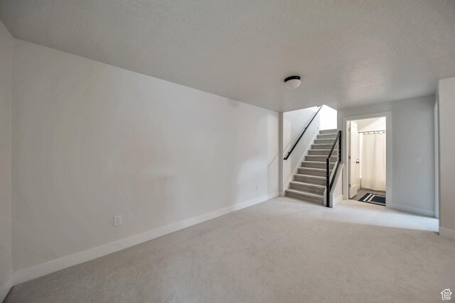 869 S Washington St Unit 101, Salt Lake City, UT 84101 - basement featuring stairs, light colored carpet, baseboards, and a textured ceiling