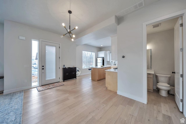 869 S Washington St Unit 101, Salt Lake City, UT 84101 - interior space with light wood finished floors, visible vents, baseboards, and an inviting chandelier