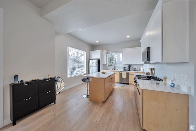 869 S Washington St Unit 101, Salt Lake City, UT 84101 - kitchen with a breakfast bar area, baseboards, stainless steel appliances, light wood-style floors, and a center island