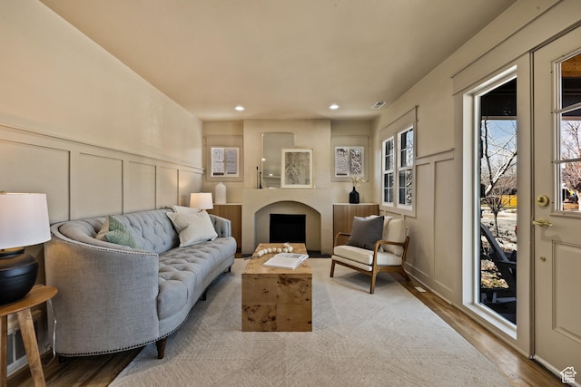 living area with a wainscoted wall, wood finished floors, a decorative wall, visible vents, and recessed lighting