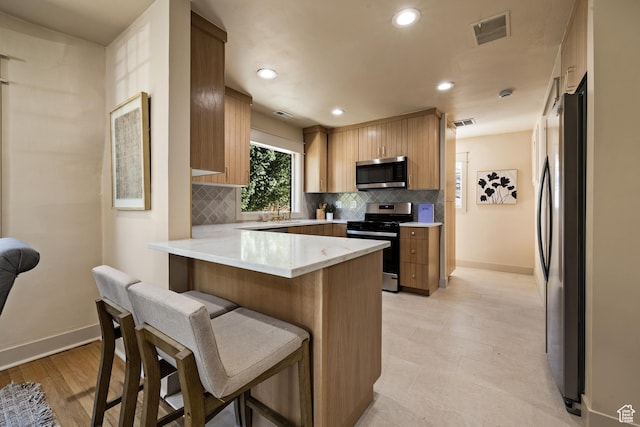 1444 E Sherman Ave, Salt Lake City, UT 84105 - kitchen with visible vents, tasteful backsplash, a peninsula, and stainless steel appliances