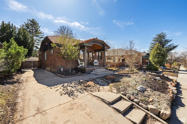 1444 E Sherman Ave, Salt Lake City, UT 84105 - view of front facade with fence, a tiled roof, brick siding, and concrete driveway