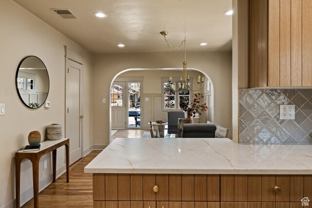 1444 E Sherman Ave, Salt Lake City, UT 84105 - kitchen with arched walkways, visible vents, brown cabinets, and a notable chandelier
