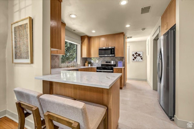 1444 E Sherman Ave, Salt Lake City, UT 84105 - kitchen with decorative backsplash, a peninsula, appliances with stainless steel finishes, and visible vents