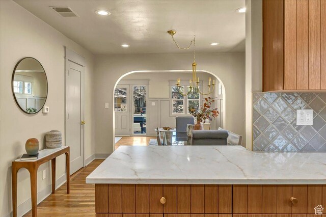 1444 E Sherman Ave, Salt Lake City, UT 84105 - kitchen featuring backsplash, a chandelier, brown cabinetry, visible vents, and arched walkways