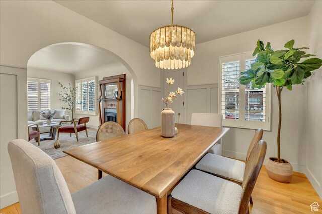 1662 E Browning Ave, Salt Lake City, UT 84105 - dining room with a decorative wall, light wood-type flooring, a fireplace, arched walkways, and a notable chandelier