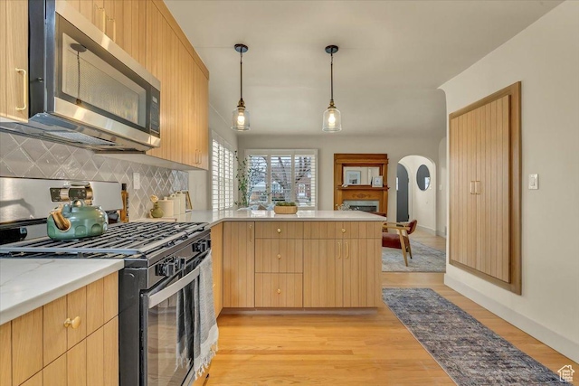 1662 E Browning Ave, Salt Lake City, UT 84105 - kitchen featuring light wood finished floors, stainless steel microwave, range with gas cooktop, a peninsula, and arched walkways