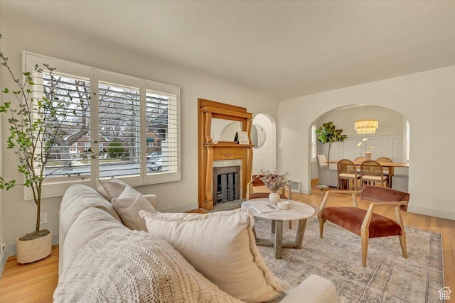 living area with wood finished floors, baseboards, visible vents, a fireplace, and arched walkways