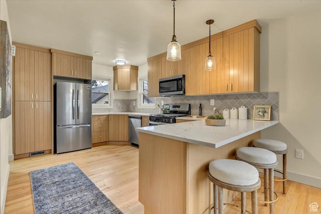 1662 E Browning Ave, Salt Lake City, UT 84105 - kitchen featuring visible vents, a peninsula, stainless steel appliances, a kitchen bar, and backsplash