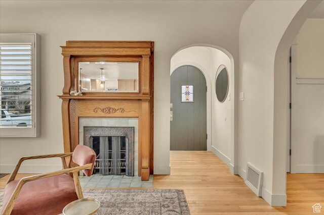 1662 E Browning Ave, Salt Lake City, UT 84105 - living area with arched walkways, visible vents, light wood finished floors, and a tiled fireplace