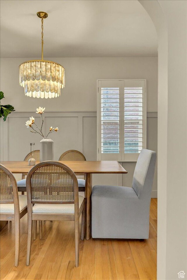 1662 E Browning Ave, Salt Lake City, UT 84105 - dining area featuring arched walkways, a decorative wall, light wood-style flooring, and a wainscoted wall