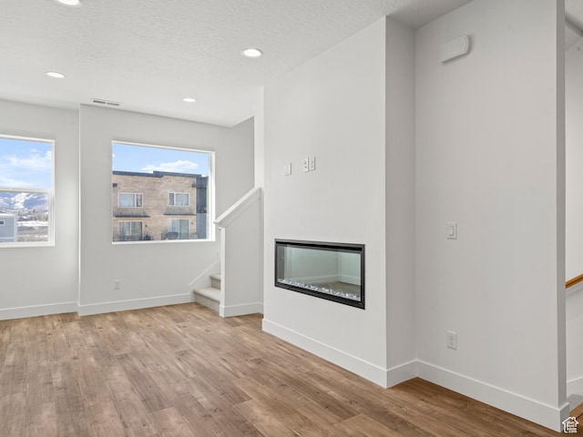 1151 Gambel Oak Way Unit 54, Park City, UT 84098 - unfurnished living room featuring stairs, a glass covered fireplace, wood finished floors, and baseboards