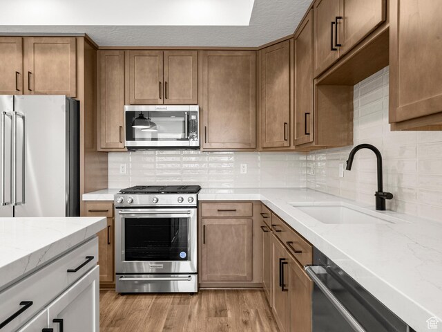 1151 Gambel Oak Way Unit 54, Park City, UT 84098 - kitchen with light wood-style flooring, a sink, backsplash, stainless steel appliances, and light stone countertops