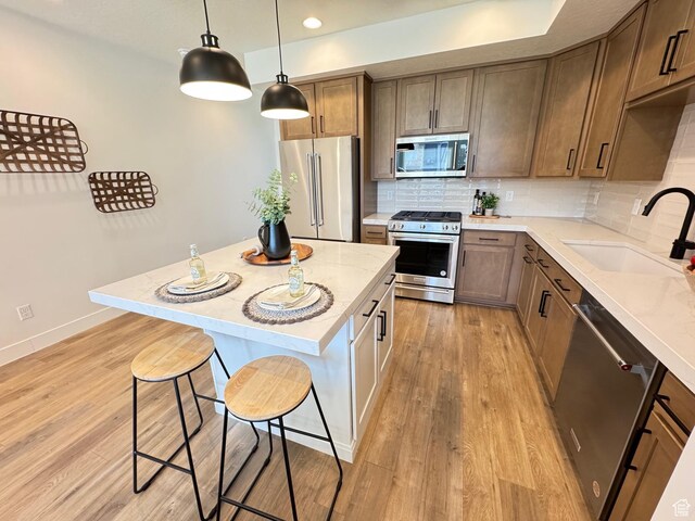1151 Gambel Oak Way Unit 54, Park City, UT 84098 - kitchen with appliances with stainless steel finishes, a sink, a breakfast bar area, light wood-type flooring, and tasteful backsplash