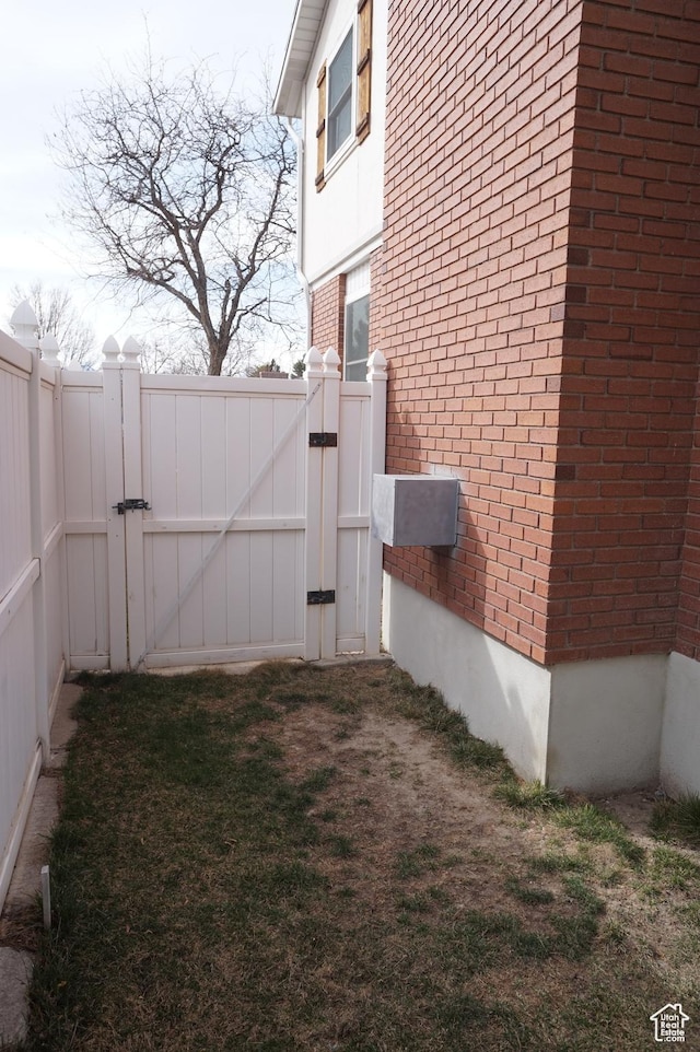 6835 S Larabrook Way, West Jordan, UT 84084 - view of side of home with fence, a gate, and brick siding