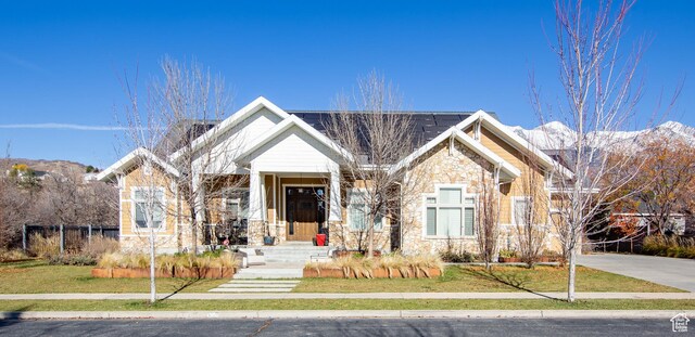 view of front of home featuring a front lawn, a mountain view, and stone siding