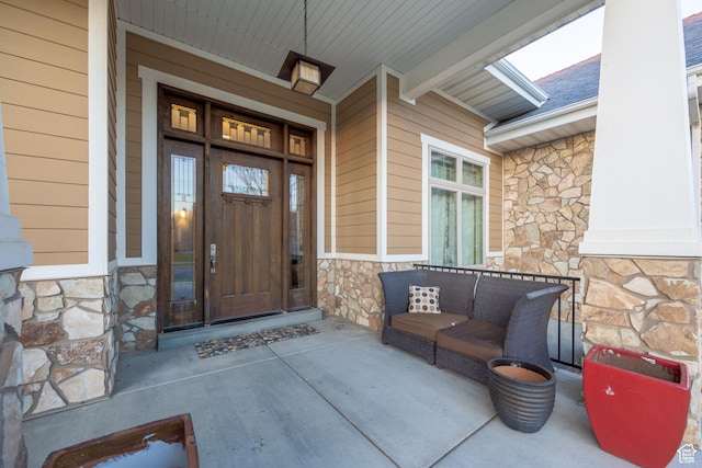 doorway to property with stone siding and roof with shingles