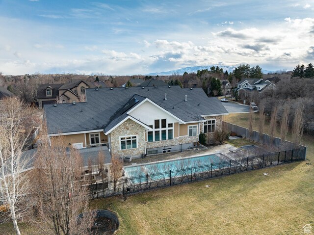 rear view of house featuring a fenced in pool, a lawn, a fenced backyard, stone siding, and a patio