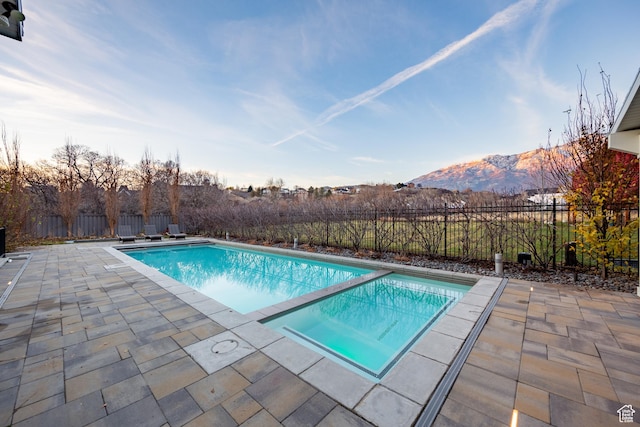view of swimming pool featuring a fenced backyard, a fenced in pool, a mountain view, and a patio