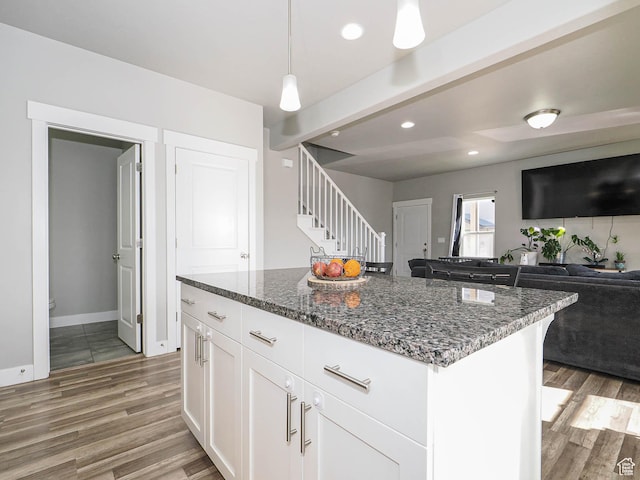 3765 E Cunninghill Dr, Eagle Mountain, UT 84005 - kitchen with dark stone countertops, a kitchen island, light wood-style floors, white cabinetry, and open floor plan