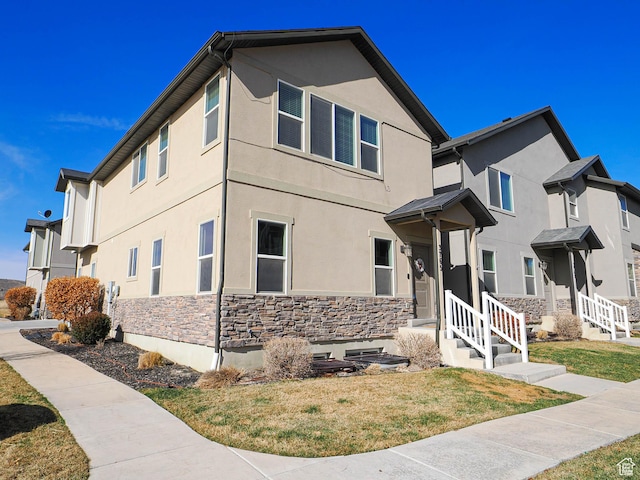 3765 E Cunninghill Dr, Eagle Mountain, UT 84005 - view of front of house with stucco siding, stone siding, and a front yard