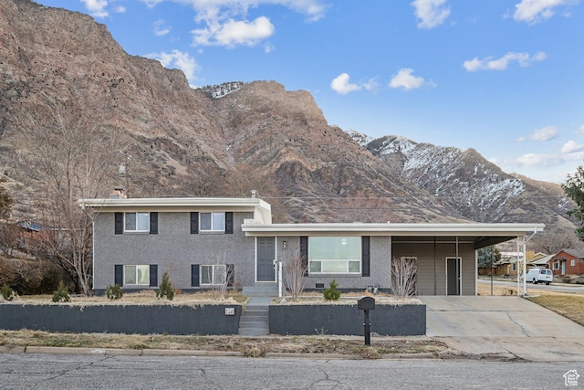 view of front of property featuring central AC, a mountain view, concrete driveway, brick siding, and a chimney