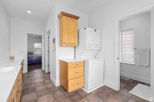 5798 W 11350 N, Highland, UT 84003 - clothes washing area with baseboards, a sink, stacked washer and clothes dryer, stone finish floor, and recessed lighting