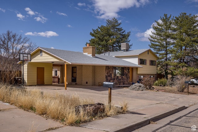 252 Hillside Dr, Moab, UT 84532 - view of front of property with driveway, central AC, a shingled roof, a chimney, and brick siding
