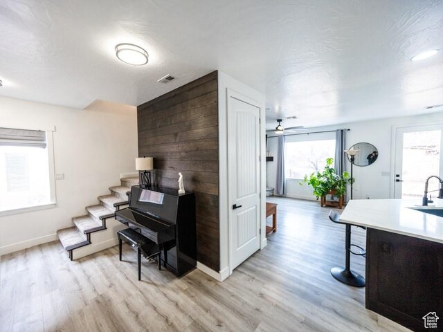 interior space featuring light wood-style flooring, a breakfast bar area, ceiling fan, and a sink