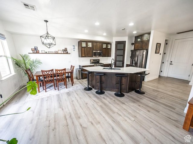 kitchen with visible vents, stainless steel appliances, light countertops, light wood-style floors, and a kitchen bar
