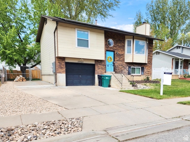 bi-level home with a garage, a gate, a chimney, and fence