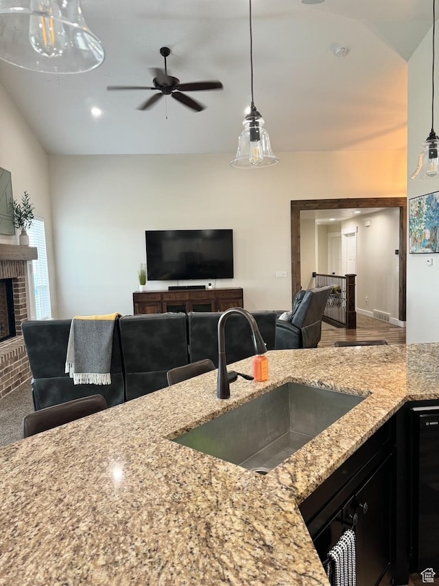5517 S 6800 W, Hooper, UT 84315 - kitchen with a brick fireplace, decorative light fixtures, open floor plan, light stone counters, and a sink