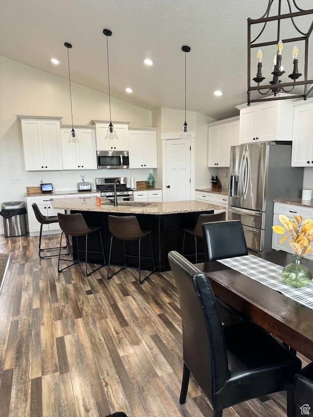 5517 S 6800 W, Hooper, UT 84315 - kitchen with a breakfast bar area, a center island with sink, lofted ceiling, dark wood-style flooring, and stainless steel appliances