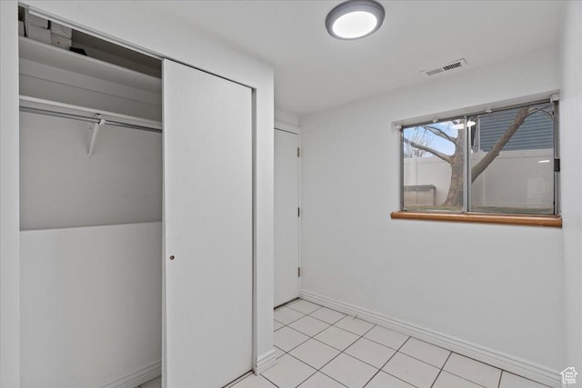 unfurnished bedroom featuring light tile patterned floors, baseboards, visible vents, and a closet