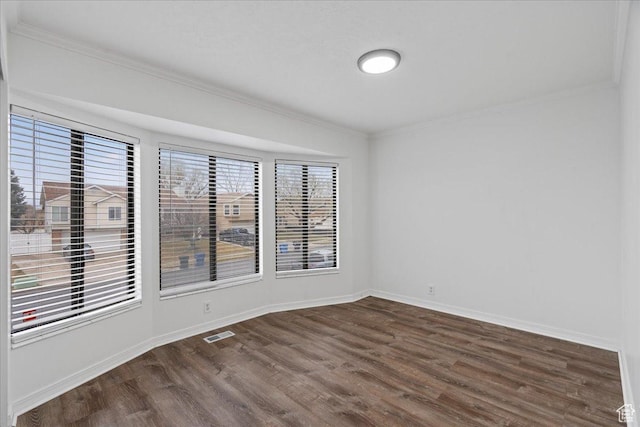 spare room with visible vents, baseboards, dark wood-style flooring, and ornamental molding