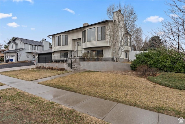 raised ranch with a front lawn and a chimney