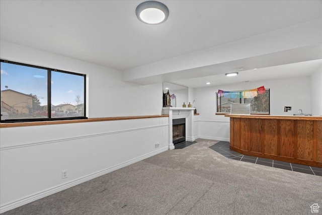 bar with a fireplace with flush hearth, a sink, bar, carpet floors, and baseboards