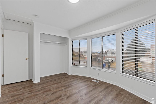 unfurnished bedroom with visible vents, baseboards, wood finished floors, and crown molding