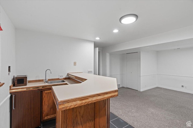 kitchen featuring light countertops, recessed lighting, carpet floors, and a sink