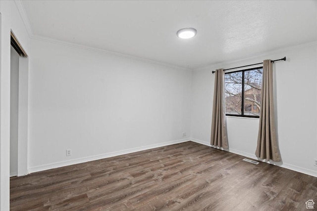 empty room featuring visible vents, ornamental molding, baseboards, and dark wood-style flooring