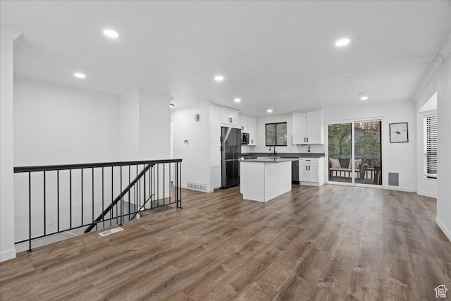 kitchen with visible vents, dark countertops, wood finished floors, white cabinetry, and freestanding refrigerator