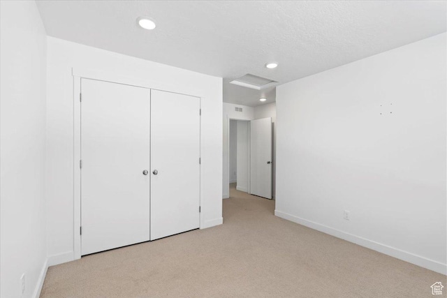unfurnished bedroom with recessed lighting, a closet, carpet, baseboards, and attic access
