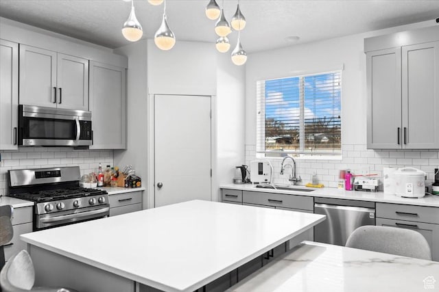 kitchen featuring a sink, light countertops, appliances with stainless steel finishes, and gray cabinetry