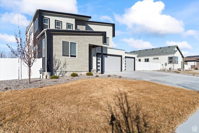 view of front of property with an attached garage, concrete driveway, a front lawn, and fence