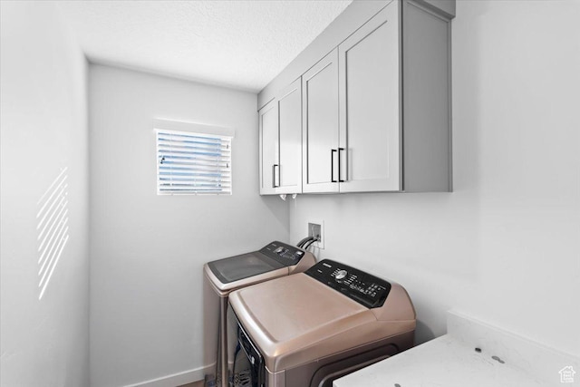 washroom featuring cabinet space, a textured ceiling, independent washer and dryer, and baseboards