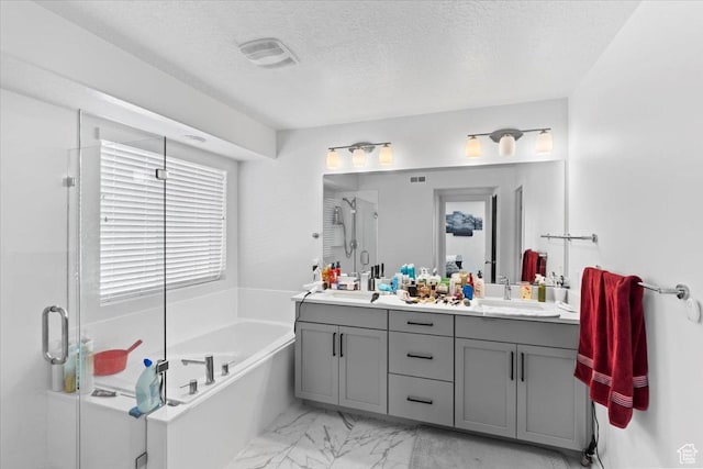 bathroom with visible vents, a shower stall, a garden tub, double vanity, and a textured ceiling